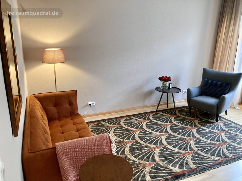 Beratungsraum im Freiraumquadrat mit rostfarbenem Sofa, blauem Sessel und warmem Licht